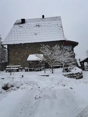 a building with a snow covered roof in a yard at Gostišče Jelka in Pohorje