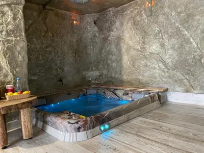 a hot tub in a cave with a wooden table at Zerko Holiday Apartment MARJETKA with WELLNESS bookable separately in Mirna