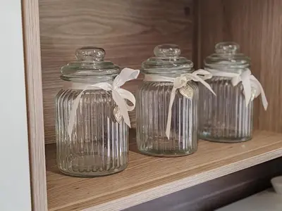 three glass jars on a shelf in a cabinet at EMIA Family House Čatež in Brežice