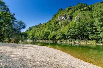 a river with a rocky shore next to a mountain at Lukec Estate in Kostel