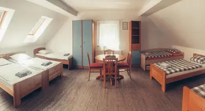 a room with two beds and a table and chairs at Apartment and rooms Maraton in Kranjska Gora