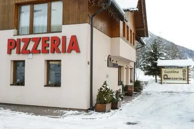 a building with a pizza sign on the side of it at Apartment and rooms Maraton in Kranjska Gora