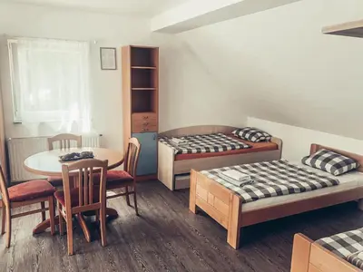 a room with two beds and a table and chairs at Apartment and rooms Maraton in Kranjska Gora