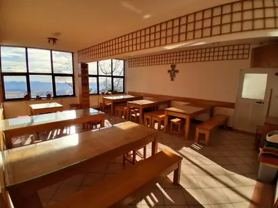 a restaurant with wooden tables and benches and windows at Tau Forest Lodge in Solkan