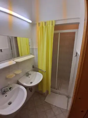 a bathroom with a sink and a shower with a yellow shower curtain at Tau Forest Lodge in Solkan