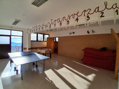 a room with a ping pong table and a sign on the wall at Tau Forest Lodge in Solkan