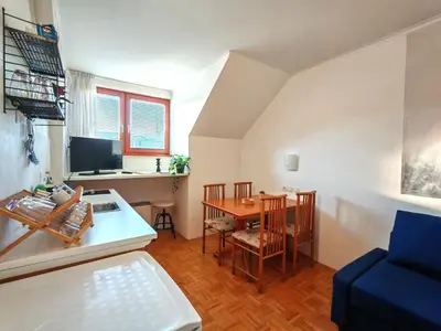 a small living room with a table and a blue couch at Apartma Roglina in Zreče