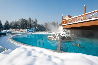 a swimming pool covered in snow with people in it at Apartma Roglina in Zreče