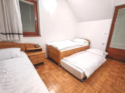a bedroom with three beds and a wooden floor at Apartma Roglina in Zreče