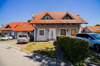 a house with cars parked in a parking lot at Holiday Home Tinkara with IR Sauna in Čatež ob Savi