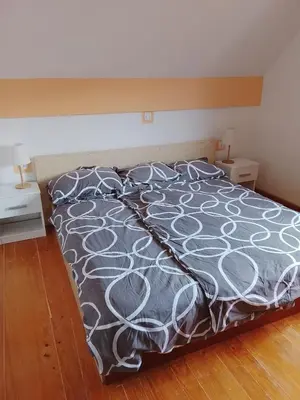 a bed with a gray and white comforter and pillows at Julijana's Holiday Home in Brežice