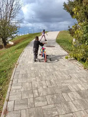 a young boy playing with a bike on a sidewalk at Julijana's Holiday Home in Brežice