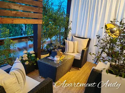 a patio with wicker chairs and a table and plants at Apartment Andy in Medvode