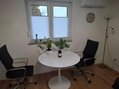 a white table and chairs in a room with a clock at Apartma Dividenda in Ptuj