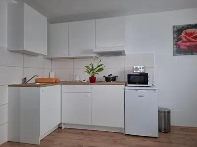 a white kitchen with white cabinets and a microwave at Apartma Dividenda in Ptuj