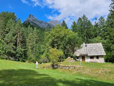 a person walking in a field in front of a house at Hiška Polhec in Bovec
