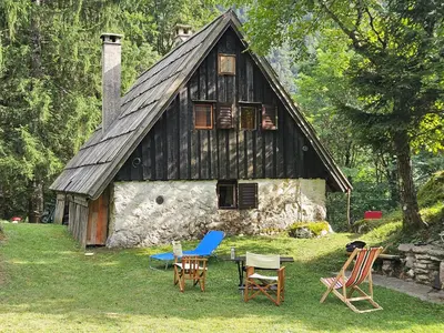 an old house with rocking chairs in front of it at Hiška Polhec in Bovec