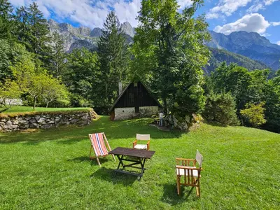a table and chairs in a field with a barn at Hiška Polhec in Bovec