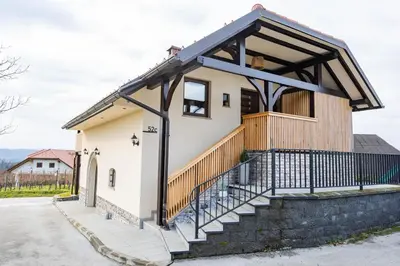 a small white house with a wooden roof and stairs at Apartment Angelina in Metlika