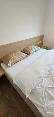 a bed with white sheets and gold pillows on it at APARTMENTS MURIC LJubljana in Ljubljana