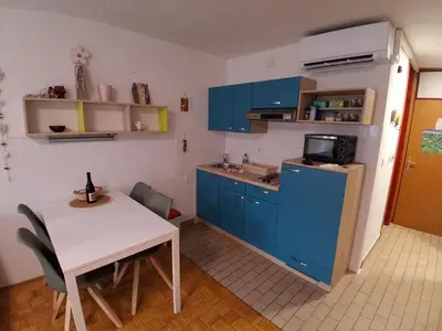 a kitchen with blue cabinets and a white table and a table and chairs at MATT Cozy Stay in Bovec