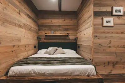 a bed in a room with wooden walls at Domačija Majer'ca in Bohinj