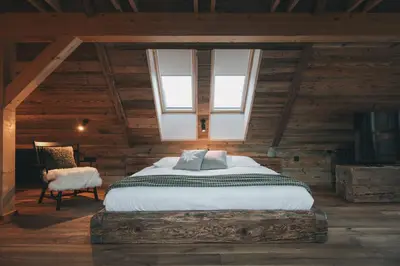 a bedroom with a bed and a chair in a attic at Domačija Majer'ca in Bohinj