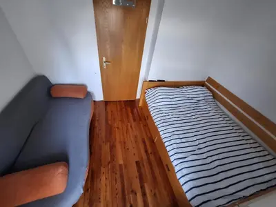 a small bedroom with a bed and a wooden floor at Apartma Ajdovka Rogla in Rakovec