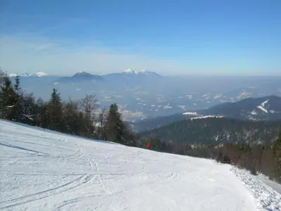 a snow covered slope with mountains in the background at Apartment Wohnung Rozika by Interhome in Slovenj Gradec