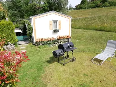 a bbq grill in a yard with a house at Apartment Stacaravan Rozika Slowenien by Interhome in Slovenj Gradec