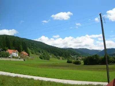 a view of a green field with mountains in the background at Apartment Stacaravan Rozika Slowenien by Interhome in Slovenj Gradec