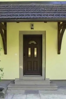 a brown door on a yellow house with stairs at Apartment Kleines Haus am Rande des Waldes by Interhome in Kranj