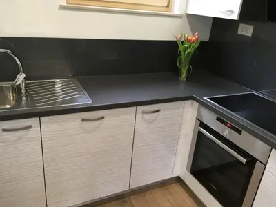 a kitchen with white cabinets and a black counter top at Apartment Wohnung Lapanja 2 mit Gemeinschaftsgarten by Interhome in Slappe dʼIdria