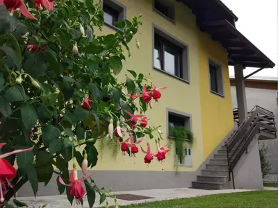 a yellow house with red flowers in front of it at Apartment mit eigener Sonnenterrasse by Interhome in Slappe dʼIdria