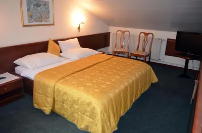 a hotel room with a bed and two chairs at Guest House Gostišče Jutriša in Rogatec