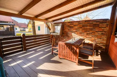 a wooden deck with a table and a brick wall at Casa Termalis in Terme Čatež in Brežice