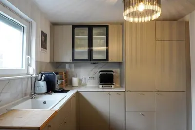 a small kitchen with white cabinets and a chandelier at Emmas apartment with private parking and balcony in Ljubljana