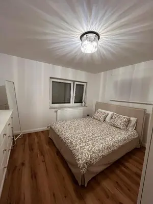 a bedroom with a bed and a chandelier at Emmas apartment with private parking and balcony in Ljubljana