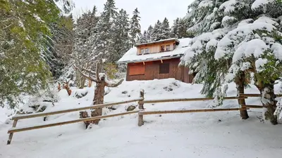 a wooden cabin with a fence in the snow at Cabin on Kobilica Off Grid Alpine Eco Retreat with Stunning Views Trail access only hike&bike in Tržič