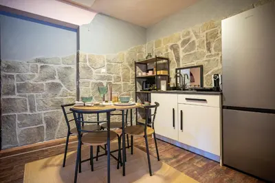 a kitchen with a table and chairs and a stone wall at Apartment Angel's Nest with Sauna and Fitness in Jesenice