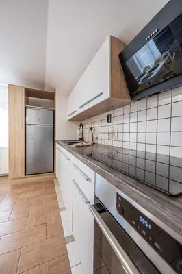 a kitchen with white cabinets and a tv on the wall at 2 Bedroom Apartment Sima with Seasonal Shared Pool in Ivančna Gorica