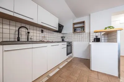 a kitchen with white cabinets and a wooden floor at 2 Bedroom Apartment Sima with Seasonal Shared Pool in Ivančna Gorica