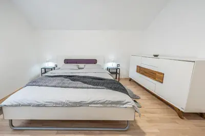 a white bedroom with a bed and a dresser at 2 Bedroom Apartment Sima with Seasonal Shared Pool in Ivančna Gorica