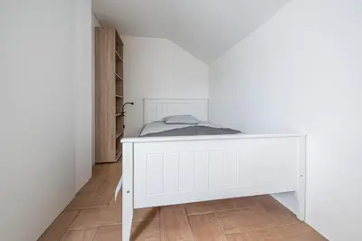 a small white bed in a room with a floor at 2 Bedroom Apartment Sima with Seasonal Shared Pool in Ivančna Gorica