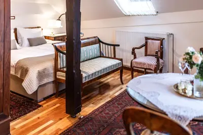 a bedroom with a bed and two chairs and a table at Historic lake view Bled apartment in Bled