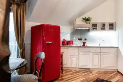 a red refrigerator in a kitchen with white cabinets at Historic lake view Bled apartment in Bled
