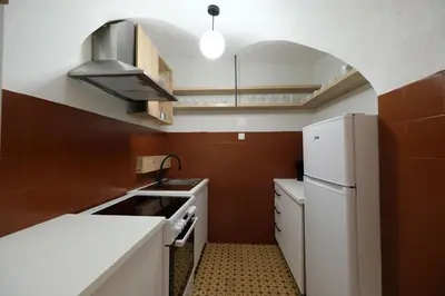 a small kitchen with a white refrigerator and brown tiles at Apartment Emona - Old Town Ljubljana in Ljubljana