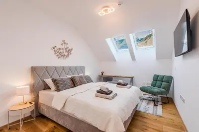 a bedroom with a large bed and a green chair at Alps2sea Suite Apartment in Bovec