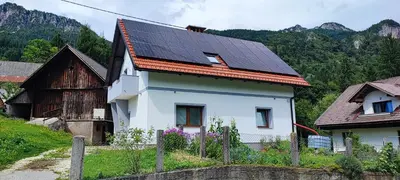 a white house with solar panels on its roof at Apartma Mlinca 2 in Mojstrana