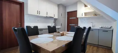 a dining room table with chairs and a kitchen at Apartma Mlinca 2 in Mojstrana